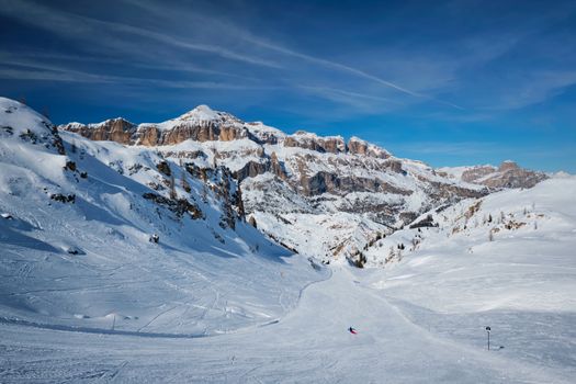 View of a ski resort piste with people skiing in Dolomites in Italy. Ski area Arabba. Arabba, Italy