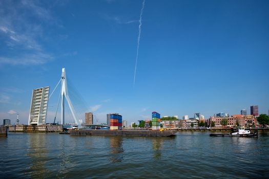 Tug boat towing barge with containers under open bascule part of Erasmusbrug bridge in Nieuwe Maas river. Rotterdam, Netherlands