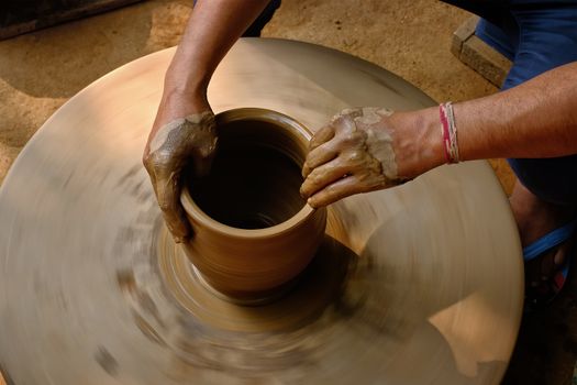 Pottery - skilled wet hands of potter shaping the clay on potter wheel. Pot, vase throwing. Manufacturing traditional handicraft Indian bowl, jar, pot, jug. Shilpagram, Udaipur, Rajasthan, India