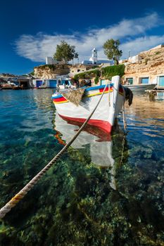 Fishing boats moored in crystal clear turquoise sea water in harbour in Greek fishing village of Mandrakia, Milos island, Greece. Horizontal camera pan