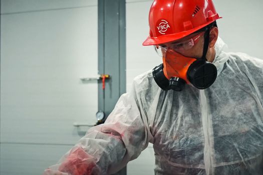 A painter in a protective suit paints.