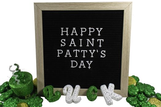 A Black Sign With a Birch Frame That Says Happy Saint Patty's Day in White Letters With Glitter Covered Four Leaf Clovers and the Word Luck Spelled Out in Front of It on a Pure White Background
