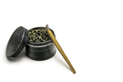 A Used Black Grinder With a Burning Marijuana Cigar Leaning On it On a Pure White Background
