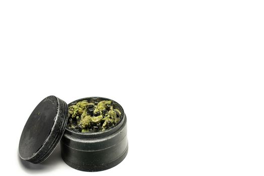 The Top Chamber of a Black and Used Grinder Full of Marijuana on a Pure White Background