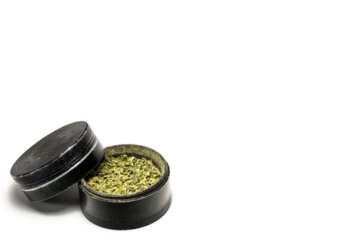 The Second Chamber of a Black and Used Grinder Full of Ground Marijuana on a Pure White Background