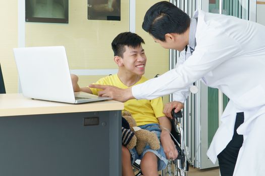 Asian doctors, adult men talking to patients with boy disabled in wheelchairs. Counseling and rehabilitation in disability in hospitals. Technology and modern medical science