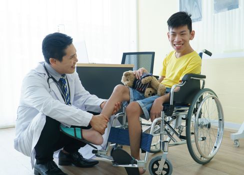 Asian doctors, adult men talking to patients with boy disabled in wheelchairs. Counseling and rehabilitation in disability in hospitals. Technology and modern medical science