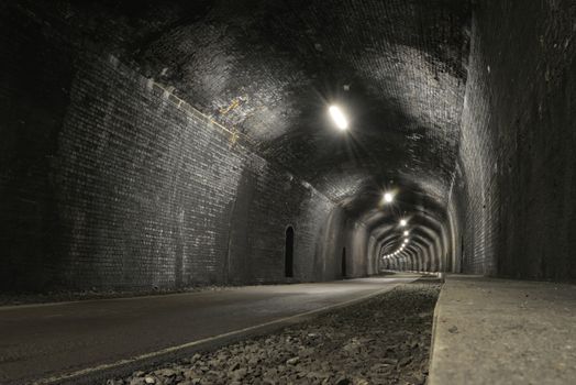 Monsal trail road passes through headstone tunnel, made of dark grey bricks, a low and wide angle image, blank and copy space. Old and rustic tunnel.