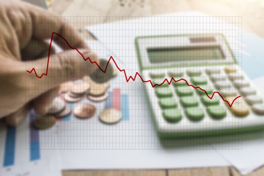 Diagram business graph with blurry Hand holding coin with calculator on graph paper