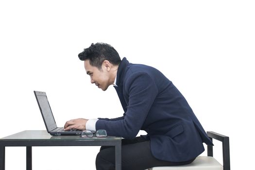 Asian Businessman sitting at a desk using a laptop on white background