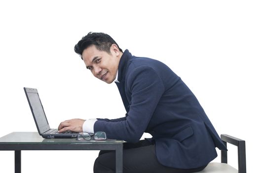 Portrait of young man sitting working on laptop  at his desk on white background
