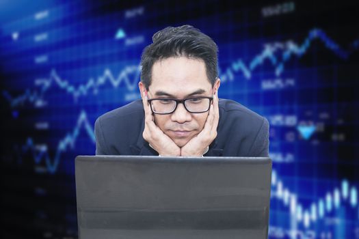 Asian business man looking laptop on business graph
