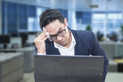 Tired business man with glasses wiping his forehead,A man is working harder to achieve new sales target.