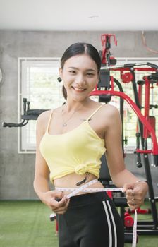 Diet fitness exercise sport sexy body happy smiling asian woman with measuring tape in fitness club, Health and body shape care concept.