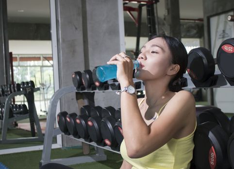 Young Asian athlete woman drinking sport drink after exercise in fitness gym, healthy lifestyle concepts