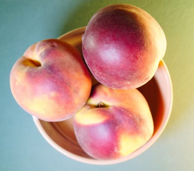 ripe peaches in a bowl on a light green background, top view