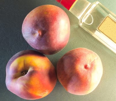 three ripe peaches on the background of green skin and a fragment of a bottle with liquid