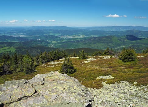 view from rocky formation in Jeseniky mountain - hills, trees, villages and blue sky and white clouds