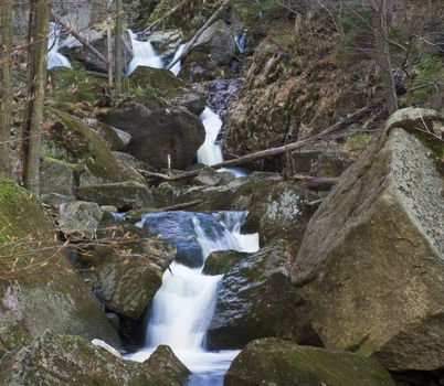 long exposure waterfal cascade in Jizerske hory, Jizera mountain, forest on Cerny Stolpich black creek in czech republic, green mossed stones, ferns and trees.