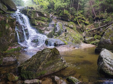 long exposure waterfall Poledni vodopad in Jizerske hory mountain forest on Cerny potok black creek in czech republic, green mossed stones and ferns