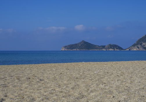 Sand and pebbles beach and turquoise sea shore at Agios Georgios Pagon at Corfu island, Greece with view on porto timony bay.