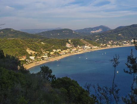 Panoramic view of Agios Georgios Pagon sand beach with green hills and sailing ships at Corfu island, Greece, sunny day blue sky.