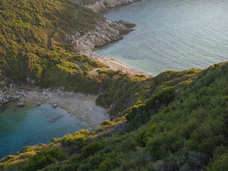 Corfu, Greece, Porto Timoni. View of the most famous double beach and bay in Afionas from the view point on the path. Sunset golden golden hour light.
