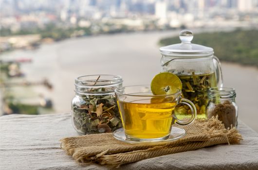 Refreshing and enjoy with A cup of lemongrass pandan tea served with brown sugar In the afternoon on beautiful river view. Thai herbal plant and healthy drinks concept. Selective focus, Copy space.