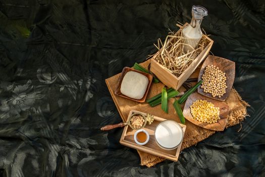Soy products : A glass of Homemade soy milk and grains (soybeans) tofu Served with brown sugar and honey on sackcloth with lighting in the morning. Alternative milk concept, Selective focus, Copy space.