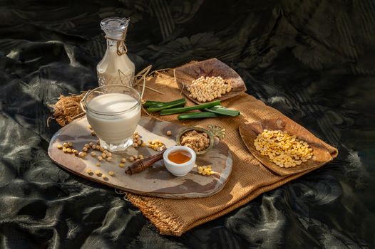 Soy products : A glass of Homemade soy milk and grains (soybeans) Served with brown sugar and honey on sackcloth with lighting in the morning. Alternative milk concept, Selective focus, Copy space.