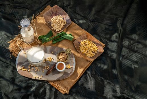 Soy products : A glass of Homemade soy milk and grains (soybeans) Served with brown sugar and honey on sackcloth with lighting in the morning. Alternative milk concept, Selective focus, Copy space.