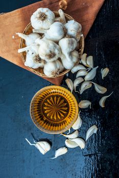 Raw garlic and honey with separate bowl on wooden surface used together for the treatment of lower high cholesterol and blood pressure and many more.