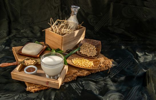 Soy products : A glass of Homemade soy milk and grains (soybeans) tofu Served with brown sugar and honey on sackcloth with lighting in the morning. Alternative milk concept, Selective focus, Copy space.