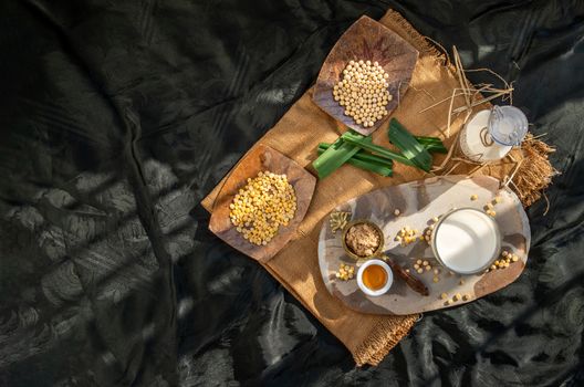 Soy products : A glass of Homemade soy milk and grains (soybeans) Served with brown sugar and honey on sackcloth with lighting in the morning. Alternative milk concept, Top view, Selective focus, Copy space.