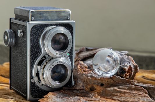 Vintage two lens photo camera with Glass crystal globe on wooden background. An idea of old camera and memory, time Nostalgia.
