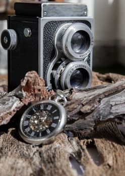 Vintage two lens photo camera with A retro pocket watch on wooden background. An idea of old camera and memory, time Nostalgia.
