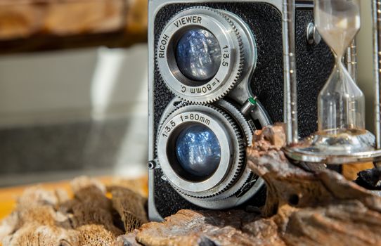 Vintage two lens photo camera with Hourglass on wooden background. An idea of old camera and memory, time Nostalgia.