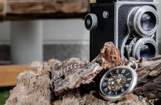 Vintage two lens photo camera with A retro pocket watch on wooden background. An idea of old camera and memory, time Nostalgia.