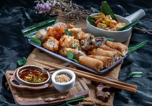 Many vegetarian food : Fried taro rolls (Taro Guangjian) and Deep fried spring rolls, Fried tofu, Fried radish, Fried taro and black beans (Zhu jiao quan or Fried taro cakes) Served with spicy sweet sauce and roasted crushed peanuts with wooden chopsticks on Ceramic dishes. Selective focus.