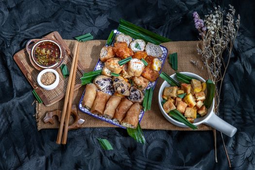 Many vegetarian food : Fried taro rolls (Taro Guangjian) and Deep fried spring rolls, Fried tofu, Fried radish, Fried taro and black beans (Zhu jiao quan or Fried taro cakes) Served with spicy sweet sauce and roasted crushed peanuts with wooden chopsticks on Ceramic dishes. Selective focus.