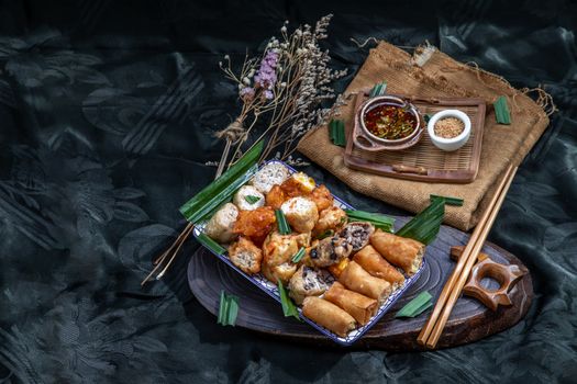 Many vegetarian food : Fried taro rolls (Taro Guangjian) and Deep fried spring rolls, Fried tofu, Fried radish, Fried taro and black beans (Zhu jiao quan or Fried taro cakes) Served with spicy sweet sauce and roasted crushed peanuts with wooden chopsticks on Ceramic dishes. Selective focus.