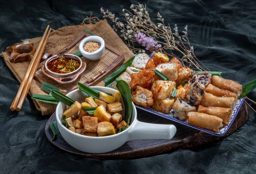 Many vegetarian food : Fried taro rolls (Taro Guangjian) and Deep fried spring rolls, Fried tofu, Fried radish, Fried taro and black beans (Zhu jiao quan or Fried taro cakes) Served with spicy sweet sauce and roasted crushed peanuts with wooden chopsticks on Ceramic dishes. Selective focus.
