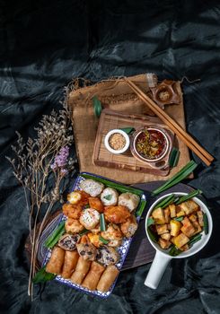 Many vegetarian food : Fried taro rolls (Taro Guangjian) and Deep fried spring rolls, Fried tofu, Fried radish, Fried taro and black beans (Zhu jiao quan or Fried taro cakes) Served with spicy sweet sauce and roasted crushed peanuts with wooden chopsticks on Ceramic dishes. Selective focus.