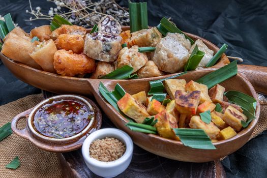 Many vegetarian food : Fried taro rolls (Taro Guangjian) and Deep fried spring rolls, Fried tofu, Fried radish, Fried taro and black beans (Zhu jiao quan or Fried taro cakes) Served with spicy sweet sauce and roasted crushed peanuts with wooden chopsticks on wooden plate. Selective focus.