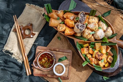 Many vegetarian food : Fried taro rolls (Taro Guangjian) and Deep fried spring rolls, Fried tofu, Fried radish, Fried taro and black beans (Zhu jiao quan or Fried taro cakes) Served with spicy sweet sauce and roasted crushed peanuts with wooden chopsticks on wooden plate. Selective focus.