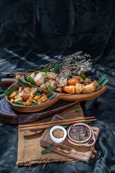 Many vegetarian food : Fried taro rolls (Taro Guangjian) and Deep fried spring rolls, Fried tofu, Fried radish, Fried taro and black beans (Zhu jiao quan or Fried taro cakes) Served with spicy sweet sauce and roasted crushed peanuts with wooden chopsticks on wooden plate. Selective focus.