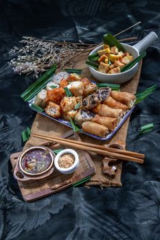 Many vegetarian food : Fried taro rolls (Taro Guangjian) and Deep fried spring rolls, Fried tofu, Fried radish, Fried taro and black beans (Zhu jiao quan or Fried taro cakes) Served with spicy sweet sauce and roasted crushed peanuts with wooden chopsticks on Ceramic dishes. Selective focus.