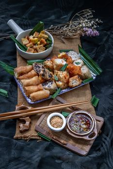 Many vegetarian food : Fried taro rolls (Taro Guangjian) and Deep fried spring rolls, Fried tofu, Fried radish, Fried taro and black beans (Zhu jiao quan or Fried taro cakes) Served with spicy sweet sauce and roasted crushed peanuts with wooden chopsticks on Ceramic dishes. Selective focus.