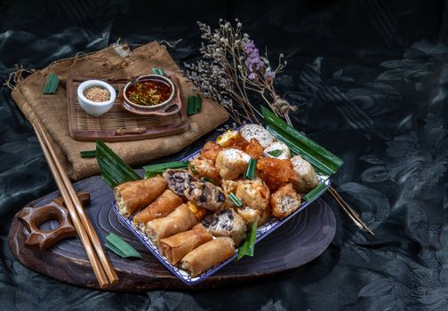Many vegetarian food : Fried taro rolls (Taro Guangjian) and Deep fried spring rolls, Fried tofu, Fried radish, Fried taro and black beans (Zhu jiao quan or Fried taro cakes) Served with spicy sweet sauce and roasted crushed peanuts with wooden chopsticks on Ceramic dishes. Selective focus.