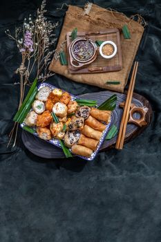 Many vegetarian food : Fried taro rolls (Taro Guangjian) and Deep fried spring rolls, Fried tofu, Fried radish, Fried taro and black beans (Zhu jiao quan or Fried taro cakes) Served with spicy sweet sauce and roasted crushed peanuts with wooden chopsticks on Ceramic dishes. Selective focus.